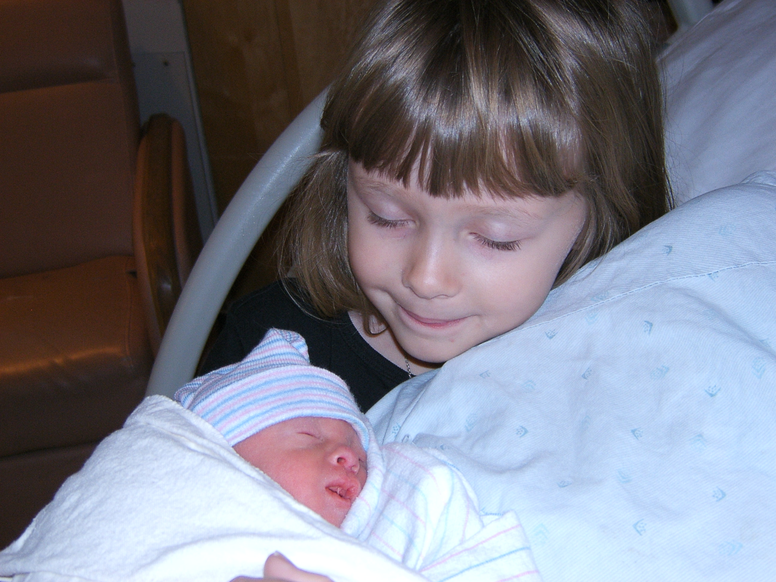 Kristin, age five, looking down at her baby sister Kennedy in the hospital